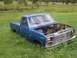 1989 Ford Bronco - This blue pickup truck appears to be abandoned in a grassy field, with its engine removed.