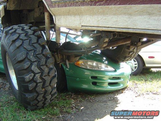 Green Dodge Avenger front end crushed under large off-road tire