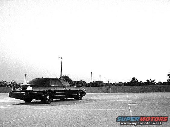 Black Ford Crown Victoria parked in an empty lot, viewed from the rear