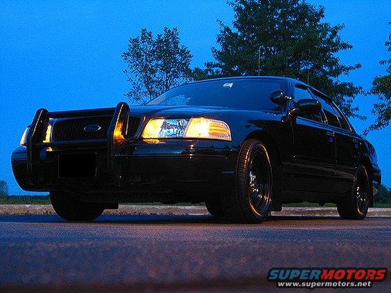 Black Ford Crown Victoria with push bar and aftermarket wheels, front view
