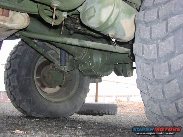 Undercarriage view of a military vehicle's rear axle, suspension, and large tire