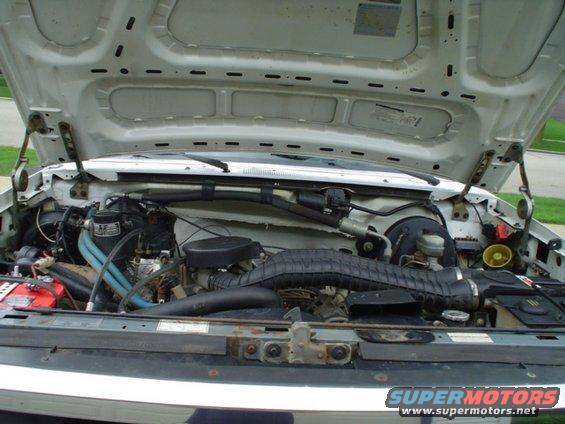 engine bay with hood open, showing engine components and battery