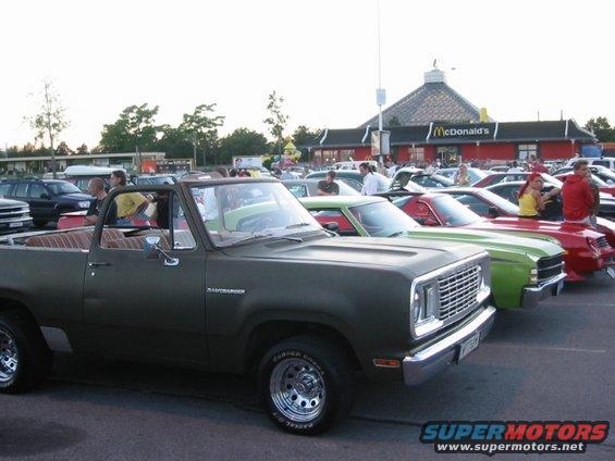 Olive green Dodge Ramcharger SUV parked in a lot with other cars, McDonald's in background