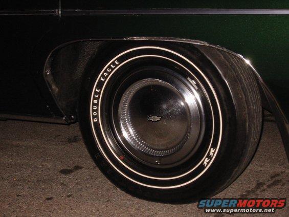 Close-up of a Chevrolet wheel with Double Eagle whitewall tires. The car is dark green