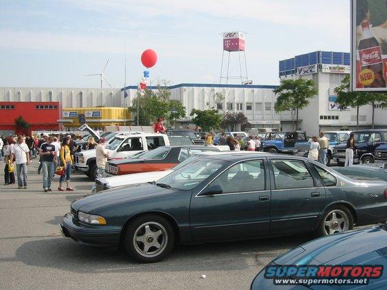 Dark green sedan parked in a lot, side view. It has a four-door body and a distinctive wheel design