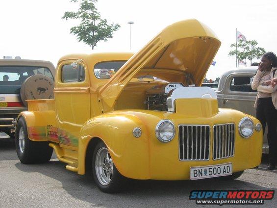 Yellow pickup truck with hood open, chrome grille, and license plate BN 500 AD