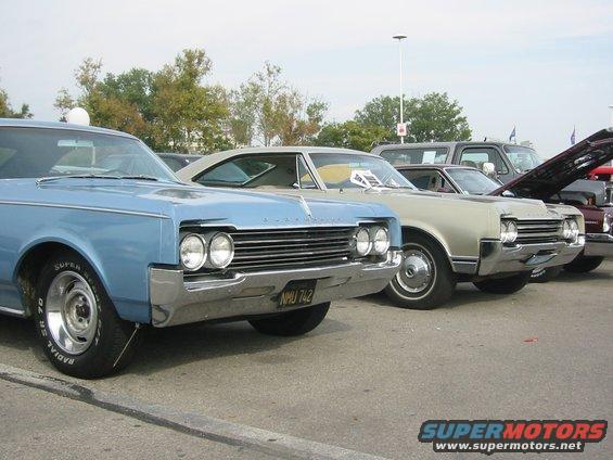 Front view of a light blue classic car, license plate NMU 742, parked in a line with other vintage vehicles