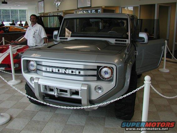 Silver Ford Bronco concept with "BRONCO" text on grille, open driver's door, and winch