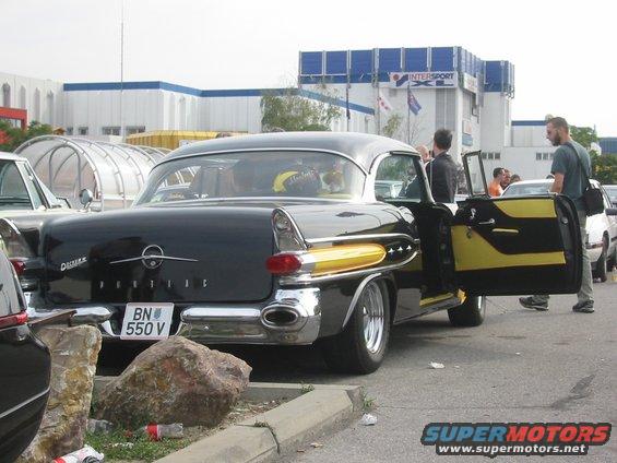 Black 1957 Pontiac Star Chief with yellow accents, rear view, driver's door open