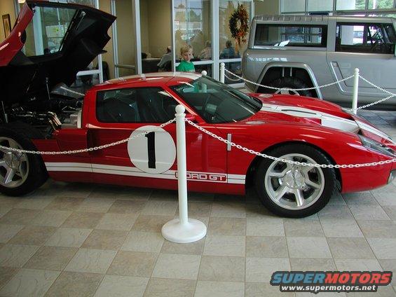 Red sports car with white racing stripes and a number 1 on the door. Another vehicle is visible behind it