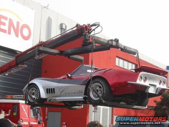 Corvette being lifted by a crane, red and silver paint, side vents, rear spoiler