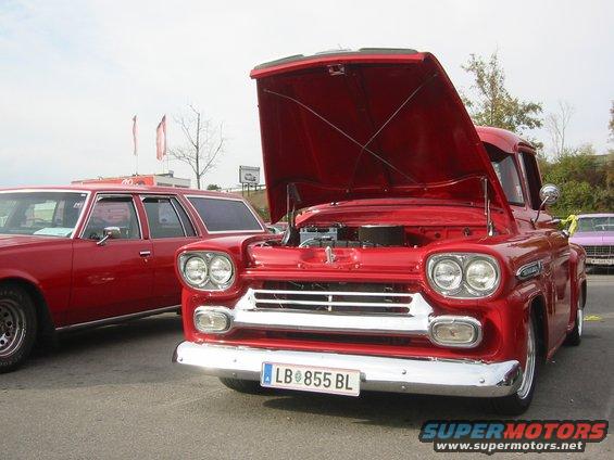 Red 1958 Chevrolet Apache pickup truck with hood open, front view, chrome grille, dual headlights