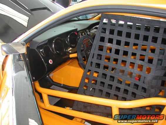 Interior of a yellow race car with a black racing net and roll cage