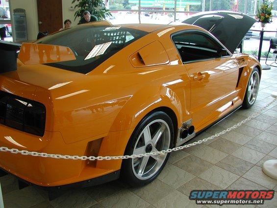 Orange sports car with hood open, custom side vents, and dual exhaust pipes