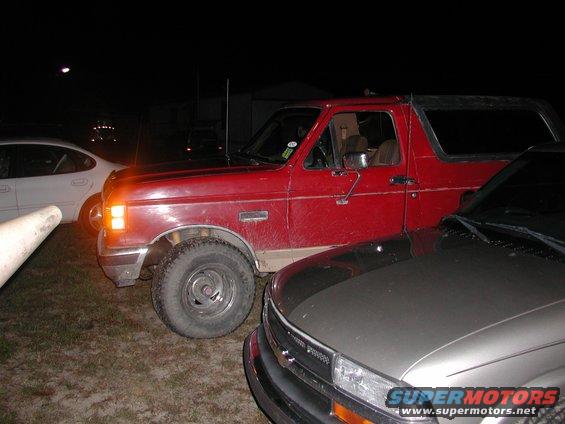 Red SUV parked next to a silver truck. Another white car is visible on the left