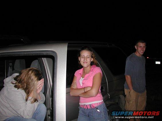 Silver SUV with open driver's door, people standing and sitting inside and outside