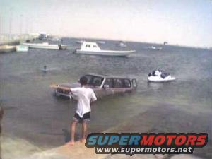 1993 Ford Bronco partially submerged in water, person standing beside it