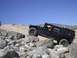 1988 Ford Bronco - A black Hummer H1 navigates a challenging rocky trail under a clear blue sky.