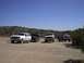 1988 Ford Bronco - Four trucks are parked in a dirt lot under a clear blue sky.