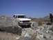 1988 Ford Bronco - A white SUV is shown maneuvering through a rocky terrain on a clear day.