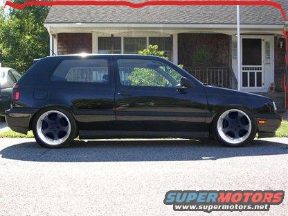 Black Volkswagen Golf Mk3 side view, lowered suspension, aftermarket wheels, parked in front of a house