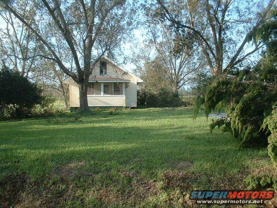 House with a screened porch surrounded by trees and a grassy yard