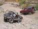 1989 Ford Bronco - A red 1987 Ford Bronco navigates a challenging off-road trail, with another modified vehicle in the foreground.