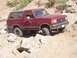 1989 Ford Bronco - 1989 Ford Bronco tackling a challenging rocky trail with its tires on uneven terrain.