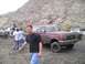1989 Ford Bronco - A group of people and vehicles, including a maroon 1989 Ford Bronco, are gathered in a dusty, rocky area.