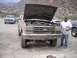 1989 Ford Bronco - A dusty 1989 Ford Bronco sits with its hood open, a man stands beside it, and other vehicles are visible in the background.