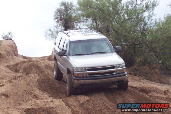 Silver SUV on a dirt hill, front grille visible, cloudy sky