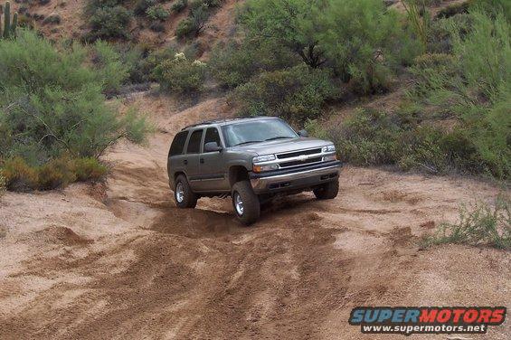 Gray Chevrolet Tahoe driving on a dirt trail in a desert landscape