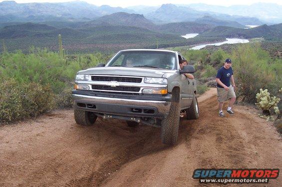 Silver pickup truck on a dirt road with mountains in the background
