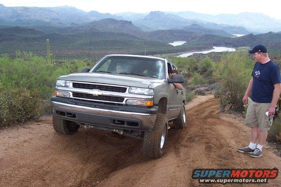 Silver 1999 Chevrolet pickup truck driving off-road with mountains in background