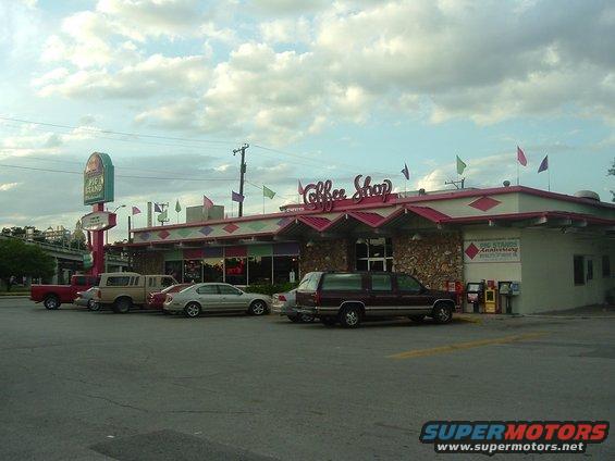 Coffee shop with parked cars and a pie stand sign