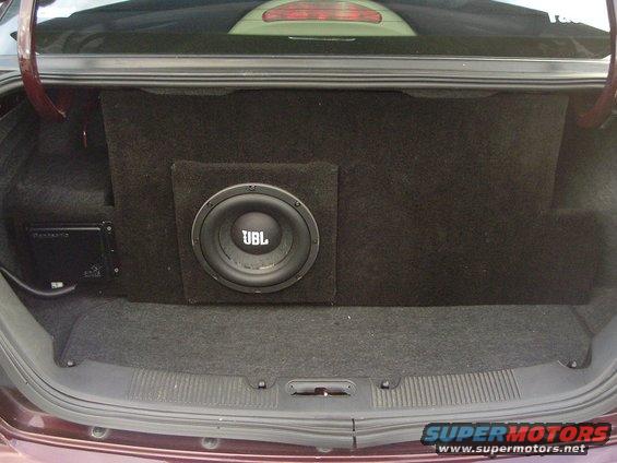 Car trunk interior with a custom subwoofer box and a JBL subwoofer, plus an amplifier on the left