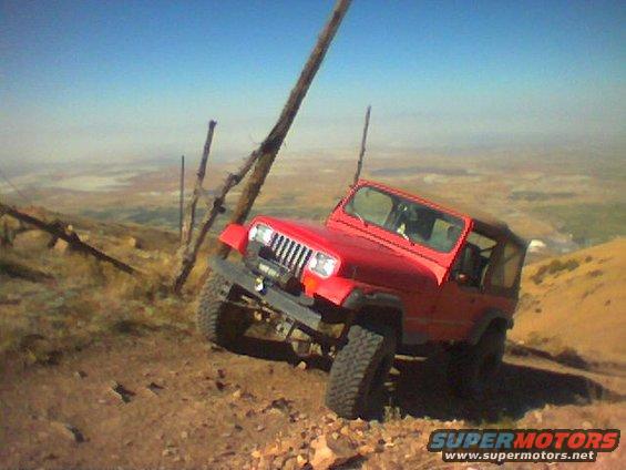 Red Jeep Wrangler on a dirt hill, leaning to the side