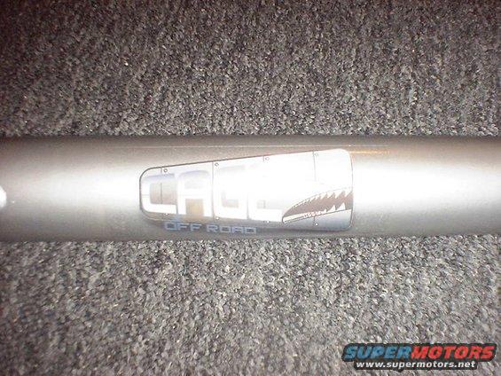 Metal tube with "CAGE OFF ROAD" logo and shark teeth graphic. Supermotors.net watermark at bottom right