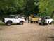 1967 Ford Bronco - Several Ford Bronco SUVs are gathered on a gravel area surrounded by trees.