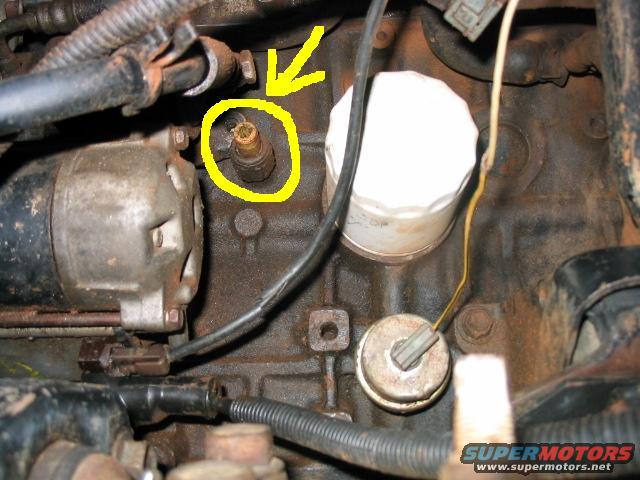 Close-up of engine block with starter motor, oil filter, and a sensor circled