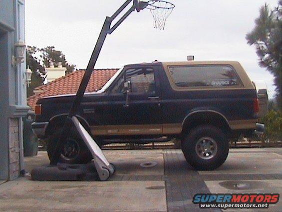 Dark blue and tan Ford Bronco parked next to a basketball hoop