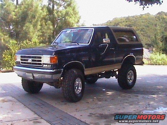 Dark blue 1991 Ford Bronco with tan trim, lifted suspension, and chrome wheels