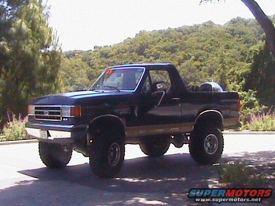 Dark blue Ford Bronco with lifted suspension and off-road tires, parked outdoors