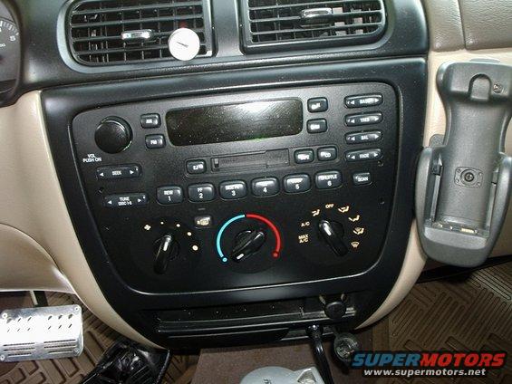 Car dashboard with radio, climate controls, and air vents. Phone mount attached to the right