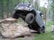 1981 Ford Bronco - Off-road vehicle navigating a difficult rock obstacle on a dirt trail.
