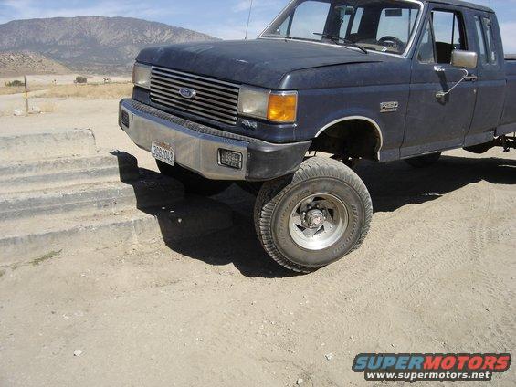 Dark blue pickup truck with chrome bumper and grille, lifted suspension