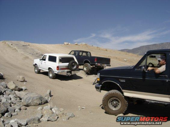 1988 Ford Bronco, dark pickup truck, and dark pickup truck driving on dirt