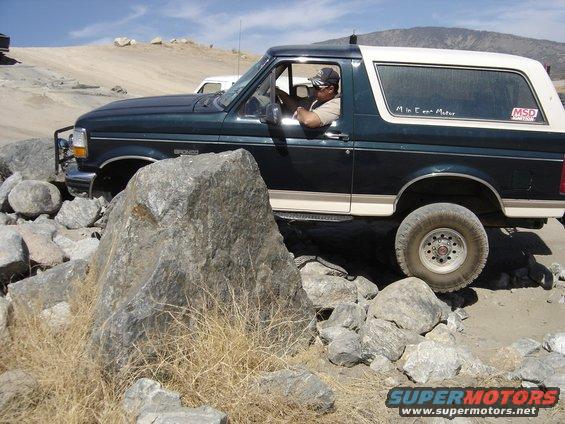 1992 Ford Bronco side view, dark green with white top, off-roading