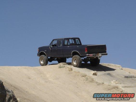 Dark blue Ford F-Series pickup truck with lifted suspension on a dirt hill