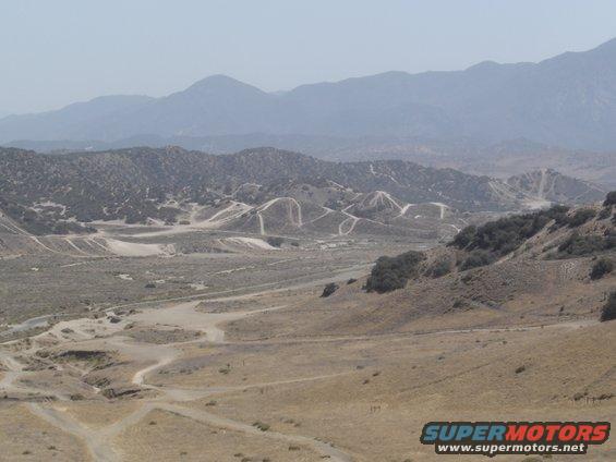 Hazy mountain range overlooks a dry, hilly landscape with winding dirt roads